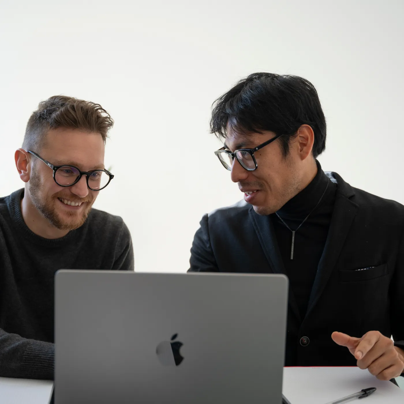 Immagine di due ragazzi discutono sorridendo su un progetto di fronte ad un laptop