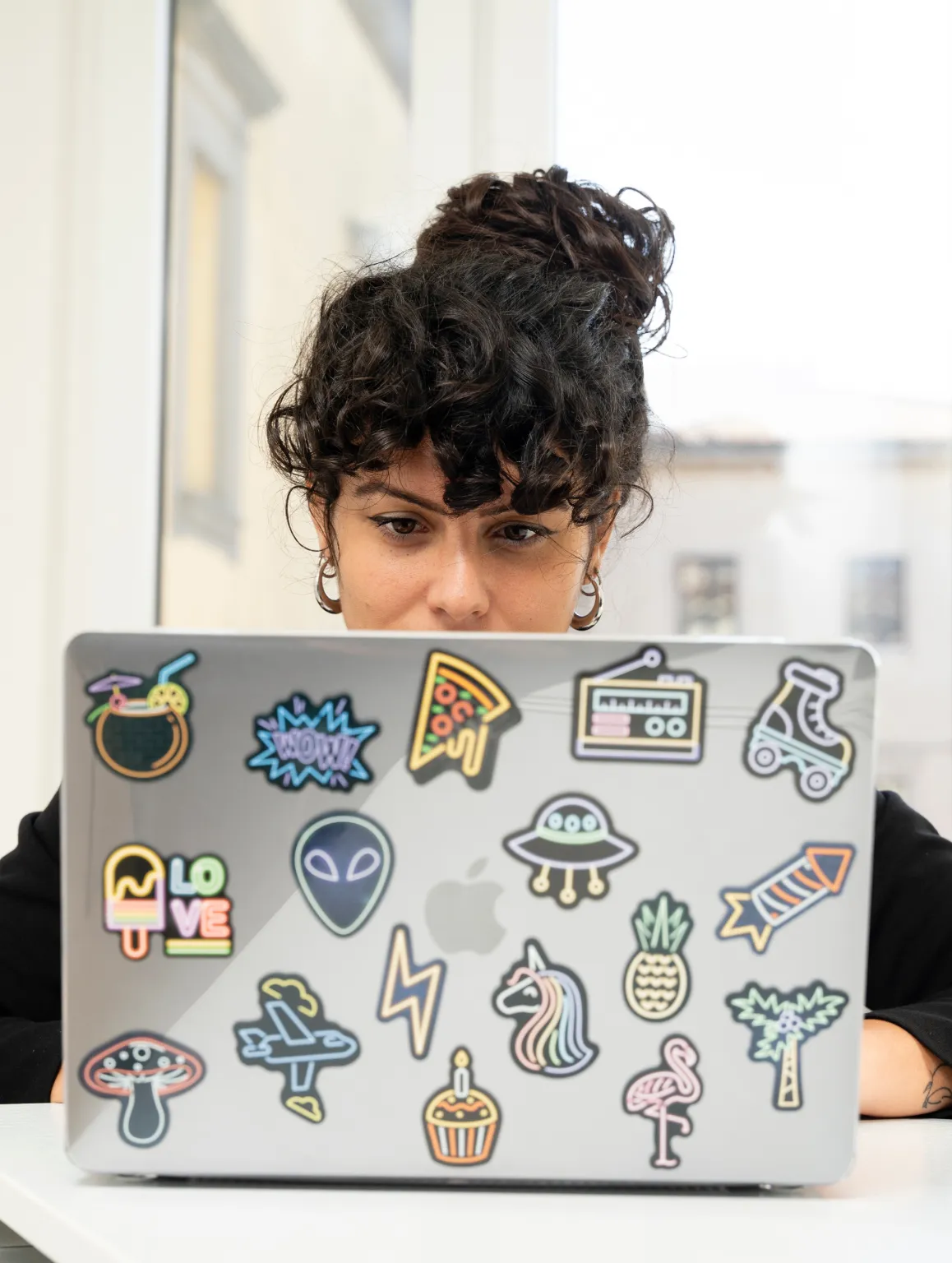 Immagine di una ragazza creativa che lavora su un portatile decorato con adesivi colorati