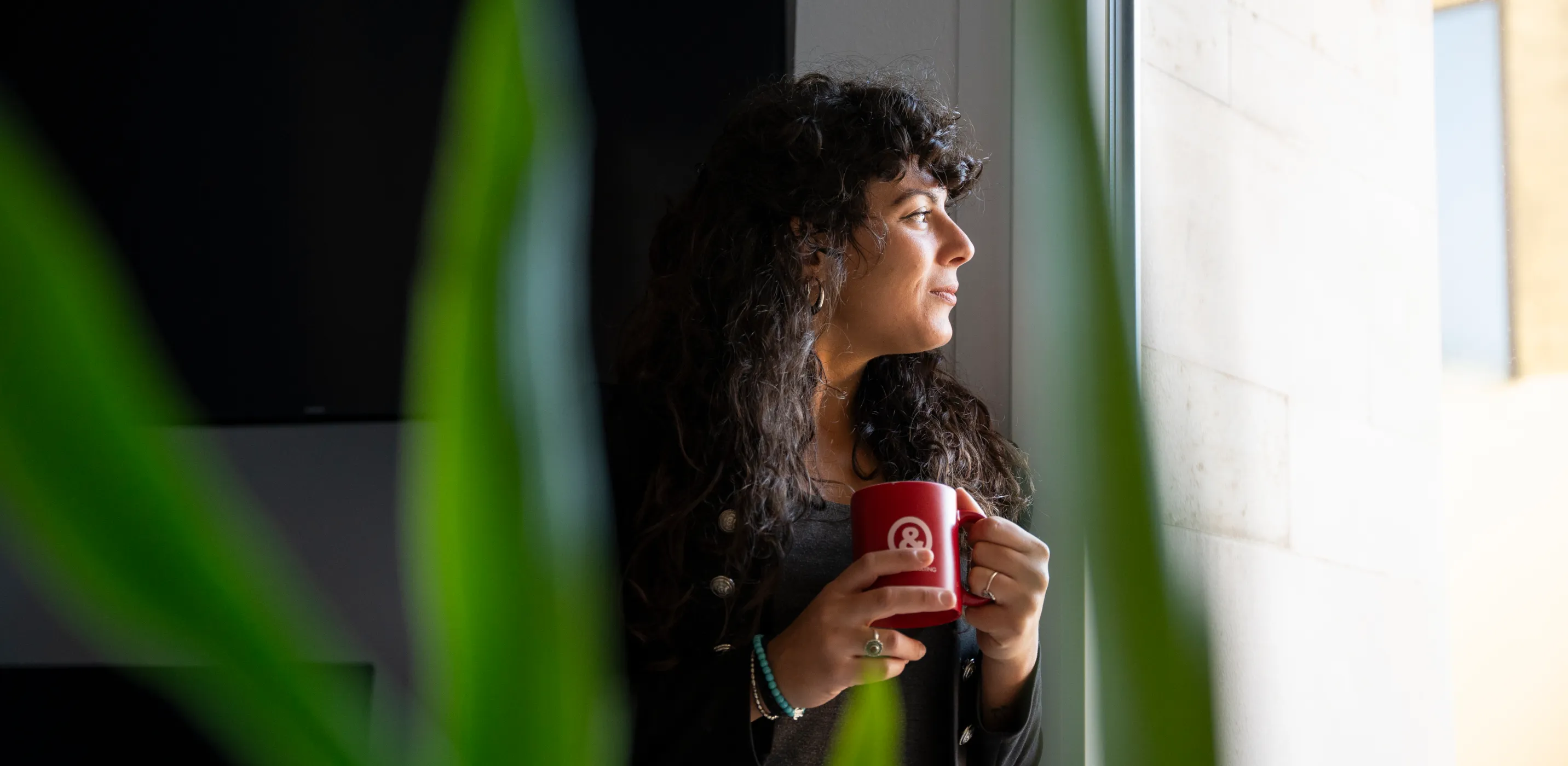 immagine di una ragazza che beve un caffè durante una pausa e guarda da una finestra verso l'esterno