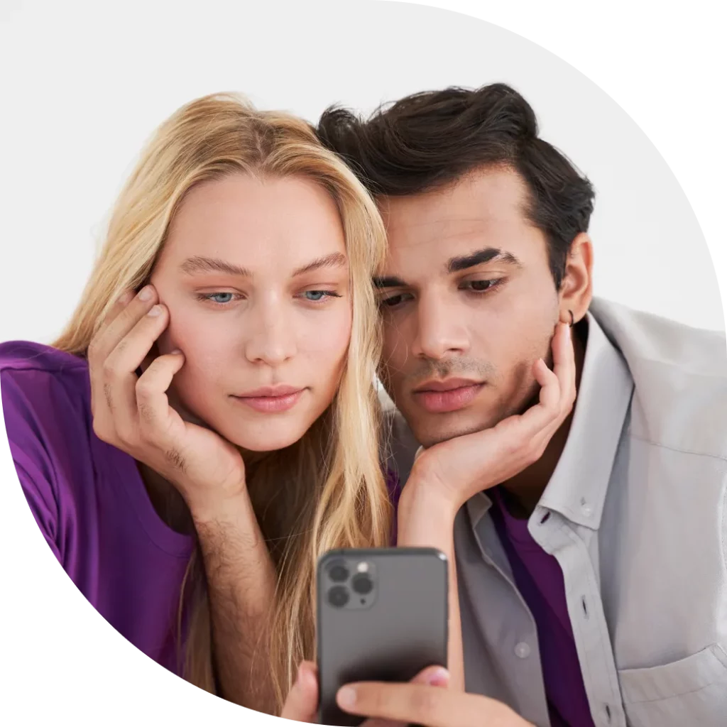 coppia che guarda un cellulare tenendosi vicendevolmente la bazza. Rappresenta visivamente i bias cognitivi nella strategia di pricing