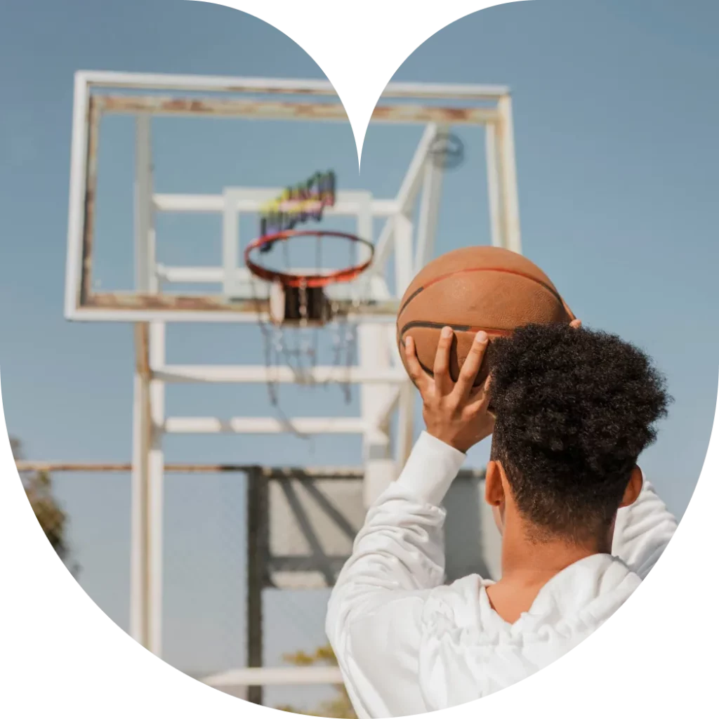 Ragazzo che tira a canestro giocando a basket
